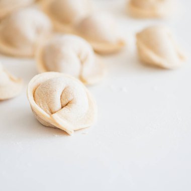 Beyaz masada pişmemiş ev yapımı pelmeni. Pelmeni, ravioli veya etli hamur tatlısı yapma süreci