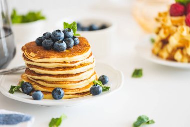 Beyaz ahşap masada taze böğürtlenli ev yapımı ricotta krepleri.