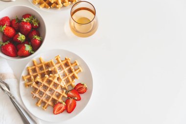 Çilekli Belçika waffle 'ları ve beyaz tabakta pudra şekeri. Kahvaltı konsepti. Uzayı kopyala Üst görünüm