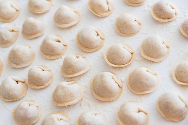 Beyaz masada pişmemiş ev yapımı pelmeni. Pelmeni, ravioli veya etli hamur tatlısı yapma süreci