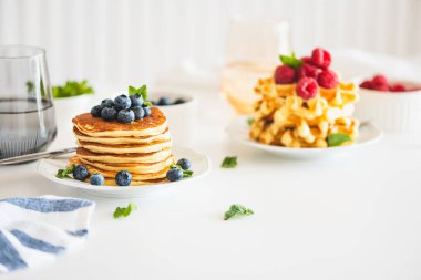 Summer breakfast. Homemade baked ricotta pancakes and Belgian waffles with fresh berries on white wooden table