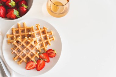 Çilekli Belçika waffle 'ları ve beyaz tabakta pudra şekeri. Kahvaltı konsepti. Uzayı kopyala Üst görünüm