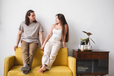 Odadaki sarı koltukta oturan çift. Yeni bir dairede aşık bir adam ve kadın. Ev konforu