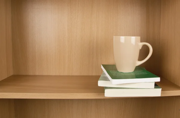 Books and cup on a shelf — Stock Photo, Image