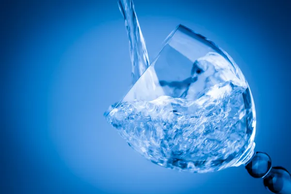 Salpicaduras de agua en un vaso azul —  Fotos de Stock