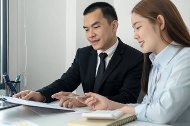 Takım elbiseli işadamı ve kadın ofis çalışanı. Panoda belge okuyacak ve ofiste birlikte çalışırken ona yeni iş projesini açıklayacak.