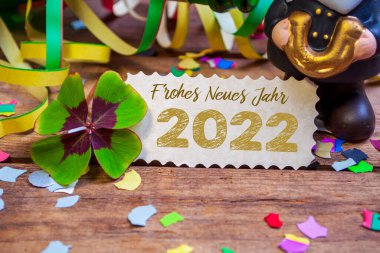 Ahşap askı etiketi ve dört yapraklı yonca ve mutlu yeni yıl için Almanca sözcüklerle kıvılcımlar - ahşap yıpranmış arka planda neue jahr 2022