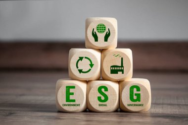 Cubes, dice or blocks with acronym ESG environment social governance on green grass clipart