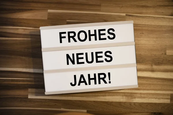 Light box  or lightbox with the german words for happy new year - frohes neues jahr on a wooden table background