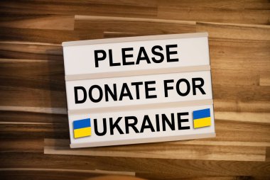 Mesaj içeren ışık kutusu veya ışık kutusu lütfen Ukrayna için ahşap masa arkasına bağış yapın.
