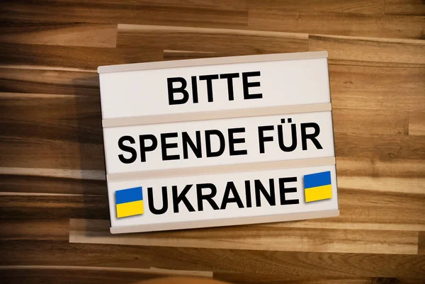 Lightbox or light box with message please donate for ukraine on wooden table background