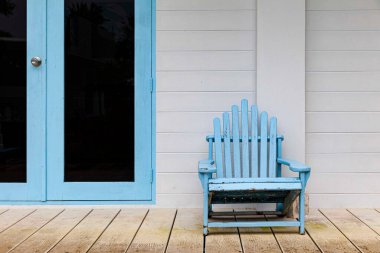 Boş mavi odun güneşliği deniz kenarındaki tatil köyünün odalarının önünde.