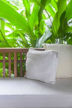 Boş kahverengi ahşap kanepe ve ev bahçesinde krem pamuk yastıklı yastıklar