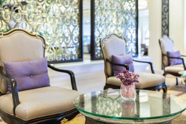 Cam bir vazodaki mor plastik çiçekler lüks bir evin oturma odasını süslüyor.