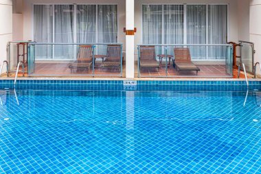 Geniş yüzme havuzu ve villanın içinde kahverengi taş zemin.