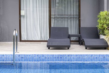 Geniş yüzme havuzu ve villanın içinde kahverengi taş zemin.