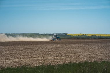 İlkbaharda tarım mahsulleri ekiliyor, traktör Ukrayna 'da güneşli bir günde çalışıyor.