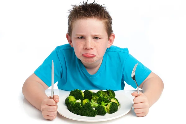 Грубий молодий хлопчик не задоволений тим, що їсть брокколі . — стокове фото