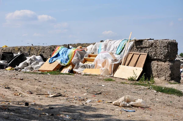 Old furniture and waste canvas in a municipal landfill near ruined wall in sunny day