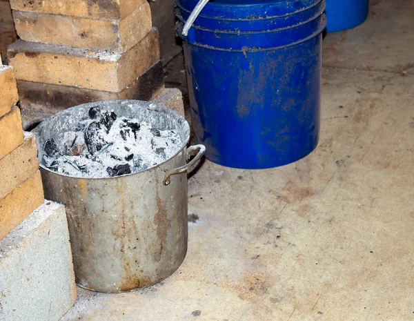 鍛冶場のセメント床にある金属製の鍋に石炭の鍛造品が洗浄され 焼損した石炭が置かれている レンガとバケツは必要な機器の一部です — ストック写真