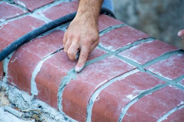 Bir zanaatkarın eli, tuğlaların arasındaki eklemleri parmağıyla dolduruyor.