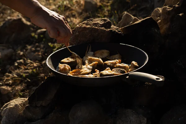 Frying fish in oil in a pan in the camp