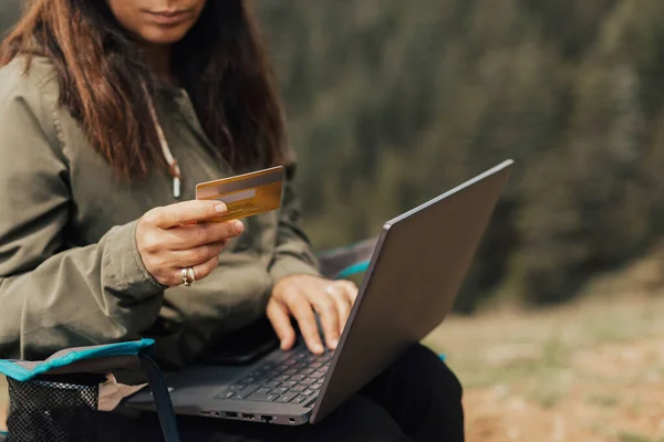 Woman working with her computer in nature, working with a computer in the forest.