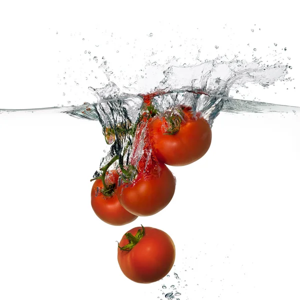 Salpicadura de tomates rojos frescos en agua aislada sobre fondo blanco — Foto de Stock