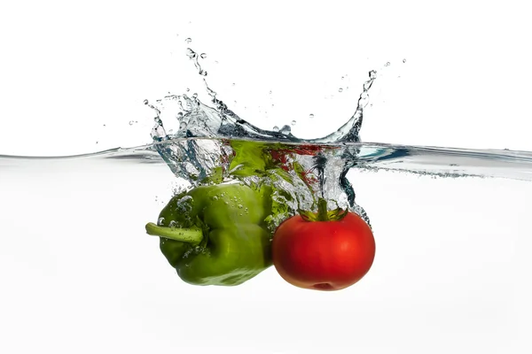 Świeże pomidory i papryka splash w wodzie na białym tle na białym tle — Zdjęcie stockowe