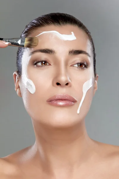Schöne Wellness-Mädchen mit Sahne auf dem Gesicht. Hautpflegekonzept — Stockfoto
