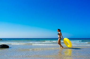 Beach Girl Walking with Yellow Float in Cadiz Beach clipart