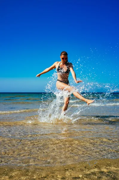 Splash. fiatal nő a víz a tengerparton élvezi. Nyáron — Stock Fotó