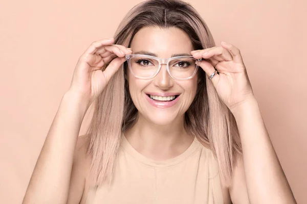 快乐微笑的美丽女人用透明的镜框调整她的眼镜眼睛穿着和视觉护理的概念 — 图库照片