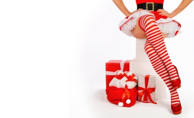 Seksi noel kadını seni. Güzel Bayan Noel Baba Noel Baba bacakları çizgili çoraplar ve yüksek topuklu ayakkabılar içinde Noel hediyelerinin yanında. Şehvetli tatil reklamı