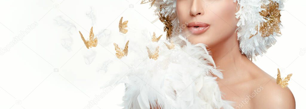 Christmas Fantasy High Fashion panorama banner with a beautiful model girl blowing gold butterflies and dainty white feathers across blank copyspace for your winter or seasonal holiday greeting.