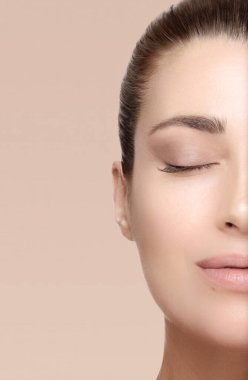 Beauty face woman with perfect healthy skin tone and glowing skin. Natural beauty with fresh clean skin. Youth and skin care concept. Vertical cropped half face isolated on beige