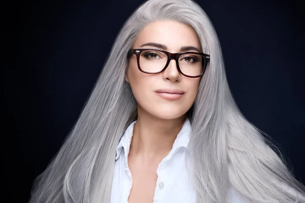 Women eyewear. Stylish silver hair woman in eyeglasses staring at camera. Beauty portrait over dark blue with copy space