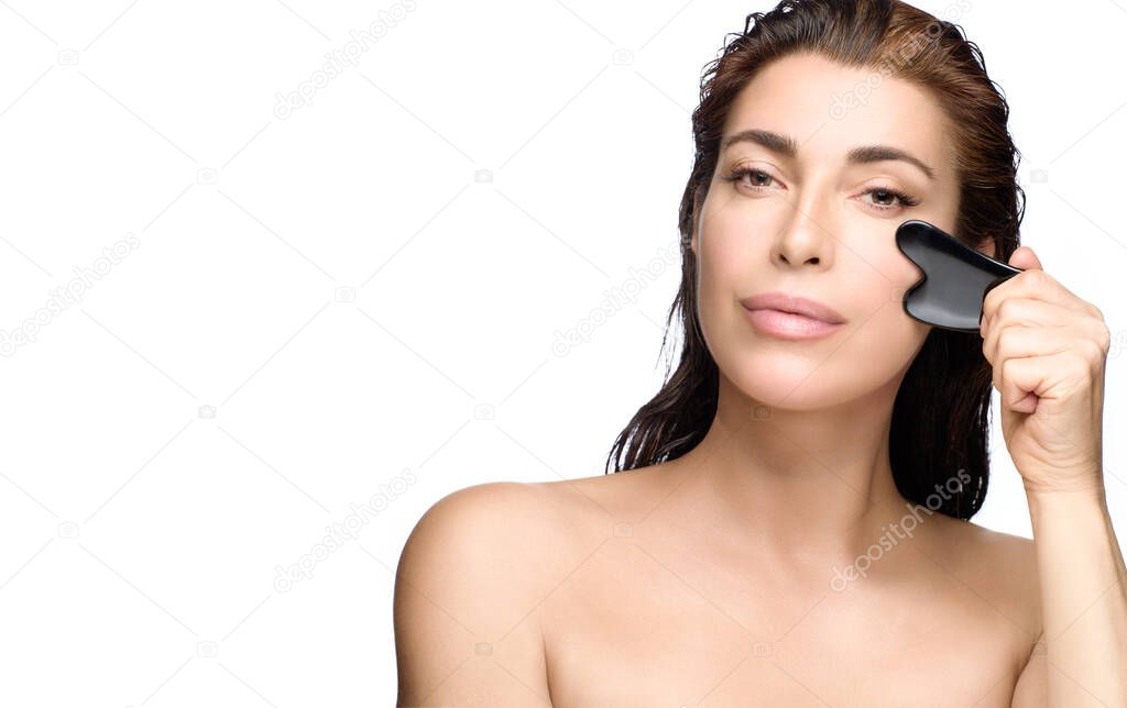 Woman doing facial massage with gua sha tool. Beauty portrait isolated on white background with copy space