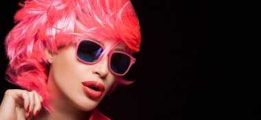 Fashion model girl with stylish pink hair and sunglasses. Dyed hair and fashion wigs concept. Isolated on black background with copy space