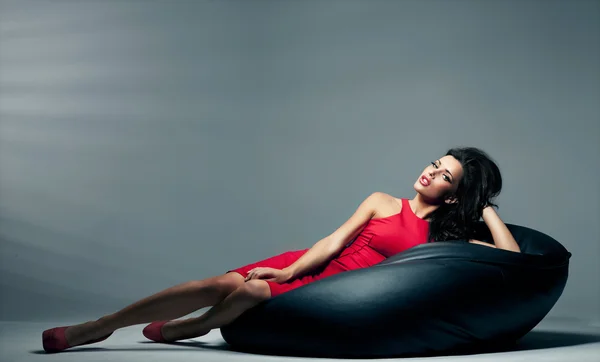 Seksowny brunetka kobieta leży na poduszce czarne — Zdjęcie stockowe