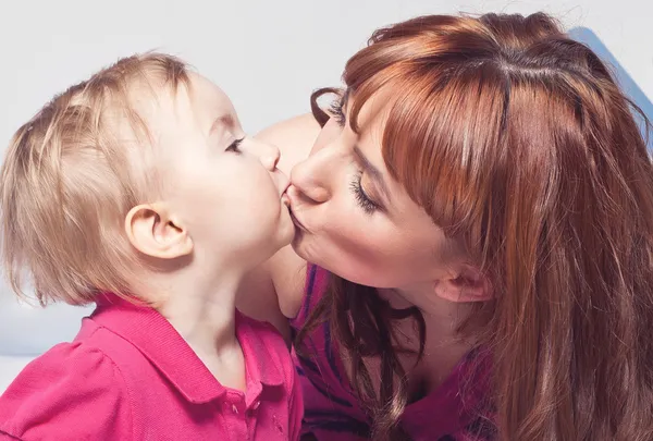Porträt eines kleinen Mädchens, das eine Mutter auf die Lippen küsst — Stockfoto