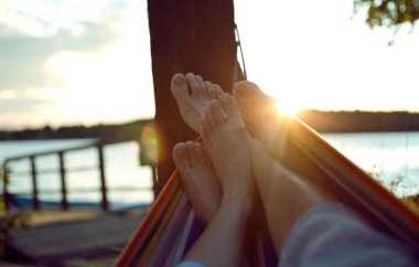 Vacation photo of couple feet relaxing on beach on hammock