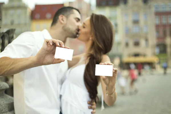 Kissing couple showing white card — Stock Photo, Image