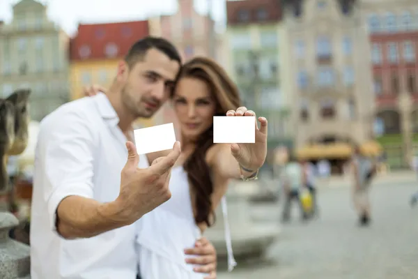 Retrato de pareja borrosa mostrando tarjeta blanca — Foto de Stock