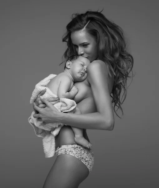 年轻的母亲亲吻婴儿的黑白照片 — 图库照片