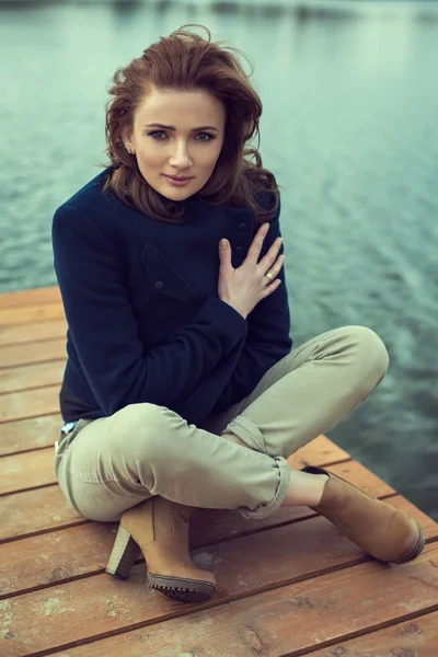 Chica joven sentada al aire libre en el lago — Foto de Stock