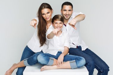 gri bir arka plana dayanır parmaklarıyla işaret eden gençler