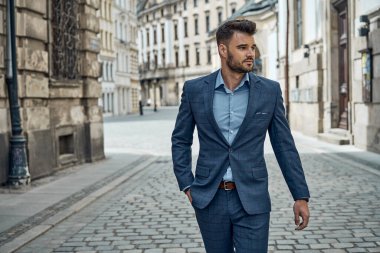 Sokakta yürüyen, takım elbiseli yakışıklı bir erkek.