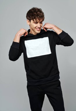 Yakışıklı adam siyah takım elbise giyer. Kapüşonlu beyaz boşluk gri arka planda izole olur.