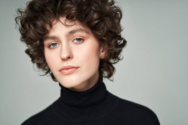 Bukleli esmer portresi yüksek yakalı kazak giyer.